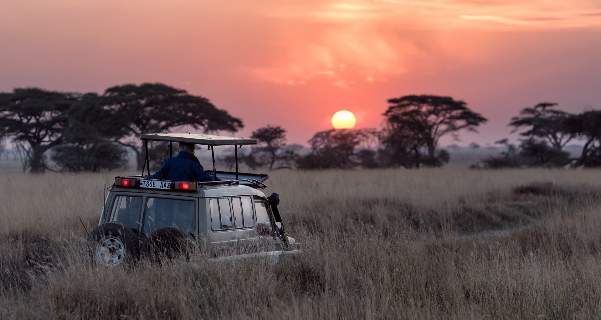 man riding on gray car during sunset