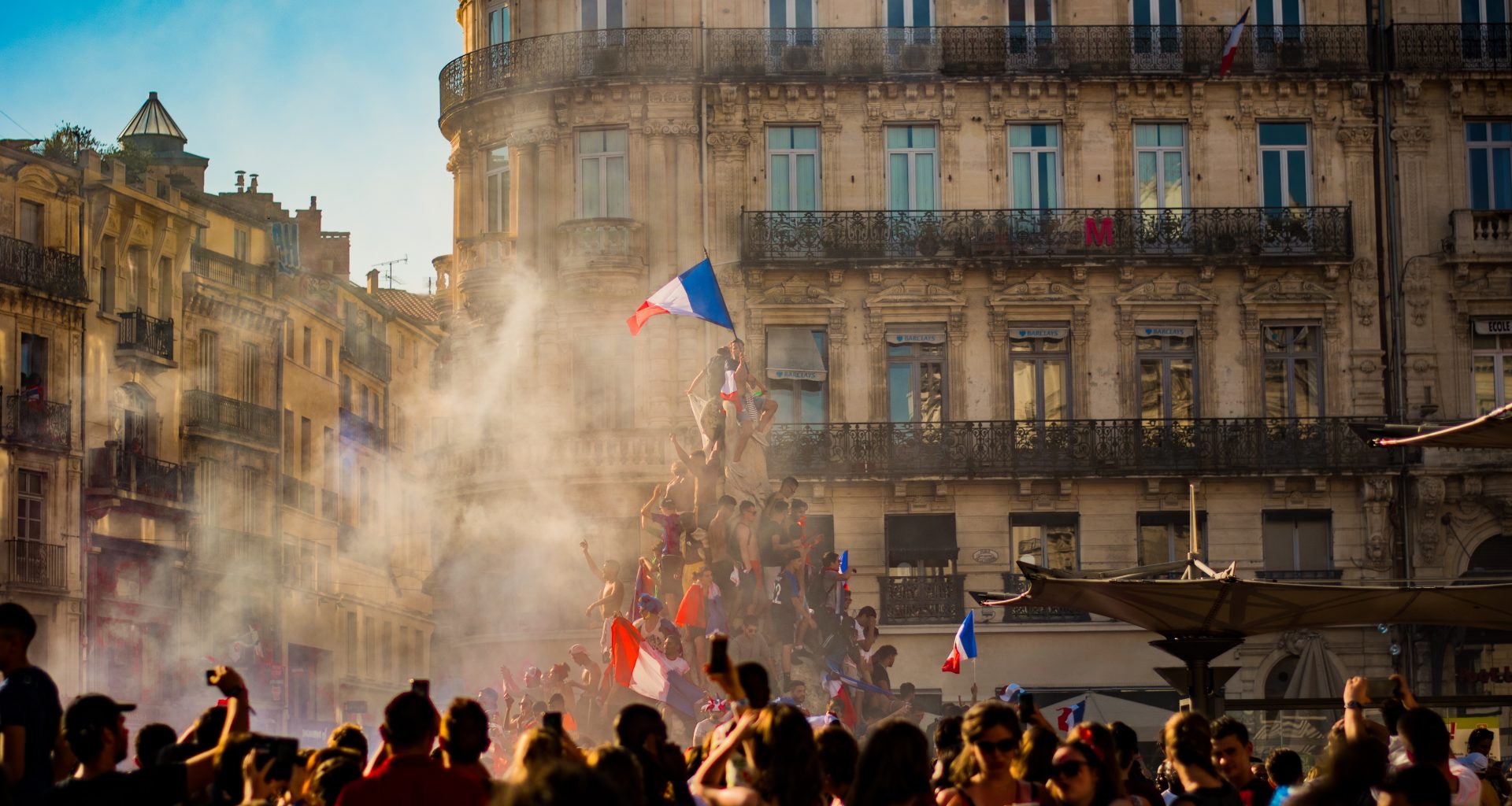 people waving flag of France near building